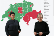 Beide Personen tragen dunkle Kleidung und stehen vor einer Präsentation, die eine Ansicht der inter-aktiven InSeMa-Landkarte zeigt. Auf dieser Landkarte sind einige Schweizer Kantone rot und die rest-lichen grün eingefärbt.